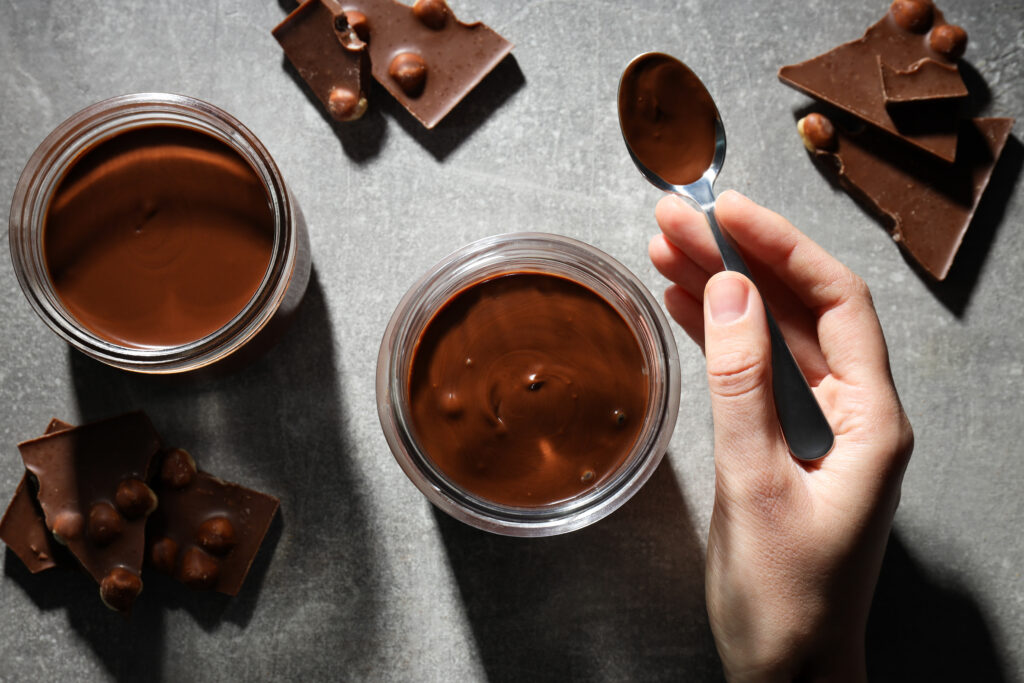 chocolate paste in a jar with chocolate on a gray background